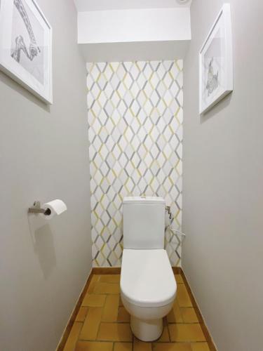 une salle de bain avec des toilettes blanches et un mur carrelé dans l'établissement Maison aux portes du centre historique de Dijon avec 3 chambres et garage, à Dijon