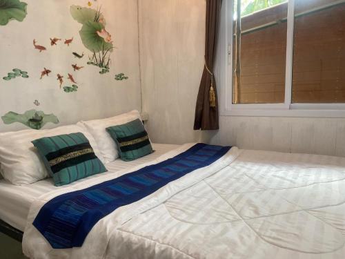 a bed with two pillows on it in a bedroom at Goodluck village house in Koh Mook