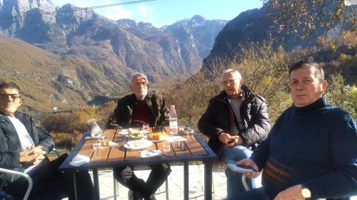 a group of men sitting around a table with food at Villa Davisol in Theth