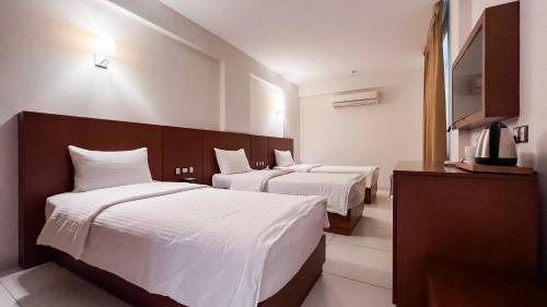 a hotel room with two beds and a flat screen tv at Coral Karbala Hotel in Karbalāʼ
