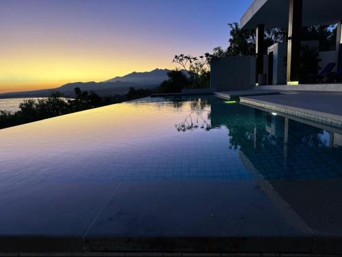 a swimming pool with a sunset in the background at Villa Salama in Tanjung