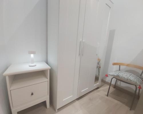 a bedroom with a white cabinet and a chair at Salvador House II in Elche