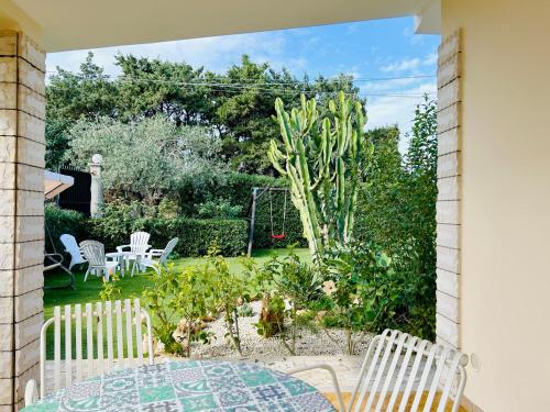a patio with a table and chairs and a garden at Garden Paradise near the sandy beach, parking & wifi in Marina dʼAvola