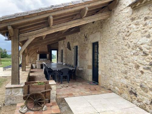 un patio avec une table et un bâtiment en pierre dans l'établissement Maison de campagne St Grégoire, à Rayet