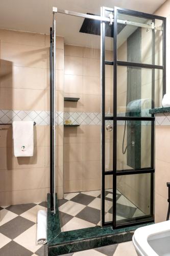 a glass shower in a bathroom with a checkered floor at Kabira Country Club in Kampala