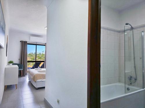 a bathroom with a bed and a tub and a bedroom at GOLDEN SUN - Sunny Balcony, Sea View, Beach, AC in Carvoeiro