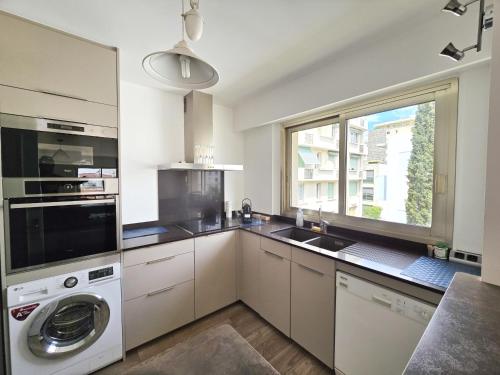 une cuisine avec une machine à laver et une fenêtre dans l'établissement 78m2 Terrasse vue mer à 50m de la Croisette, à Cannes