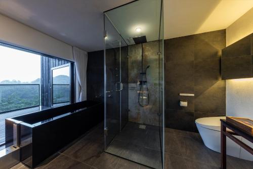 a bathroom with a glass shower with a tub and a sink at 時地人 jijijin MATSUYAMA in Tobe