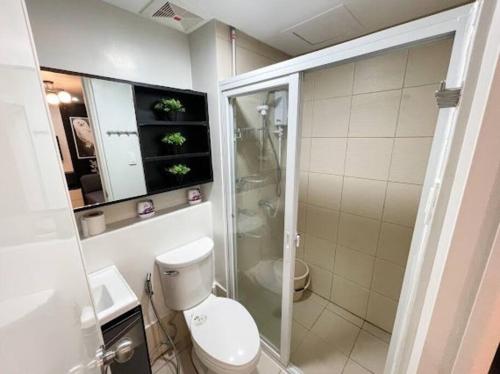 une salle de bain avec toilettes et douche en verre dans l'établissement The Common Room at Pine Suites Tagaytay, à Tagaytay