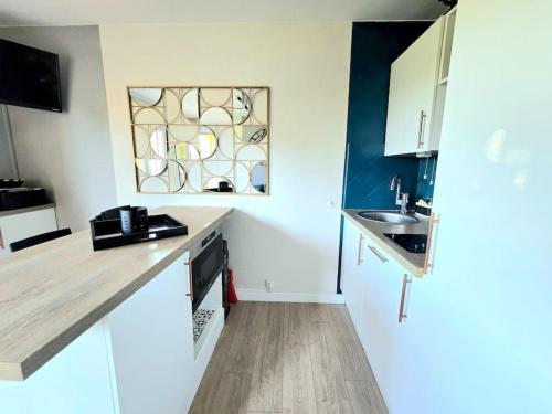 une cuisine blanche avec un évier et une fenêtre dans l'établissement Appart cosy - terrasse - clim - piscine, à Roquebrune-sur Argens