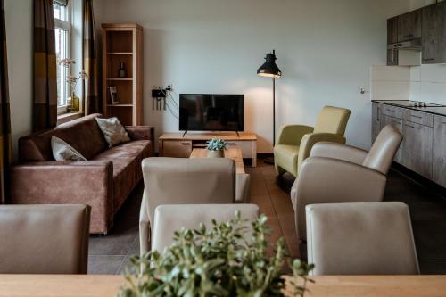 a living room with a couch and chairs and a tv at Recreatie Landgoed Terlingerhoeve in Noorbeek