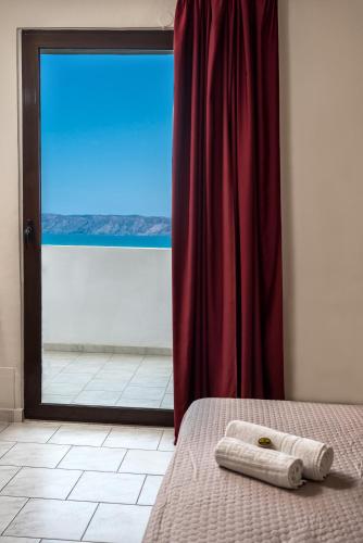 a bed in a room with a red curtain and a window at Mirtilos Studios & Apartments in Kissamos