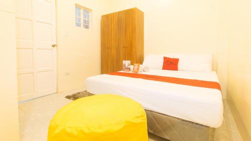 a bedroom with a large bed with a yellow stool at RedDoorz at V-Cloud Hills near De La Salle Dasmarinas Cavite in Dasmariñas