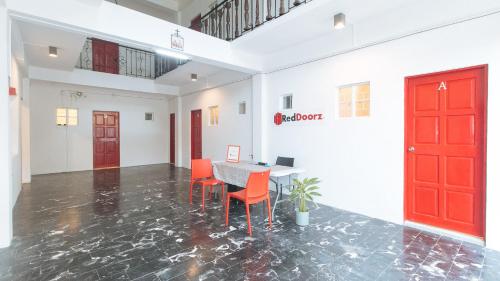 a room with a table and chairs and a red door at RedDoorz at V-Cloud Hills near De La Salle Dasmarinas Cavite in Dasmariñas