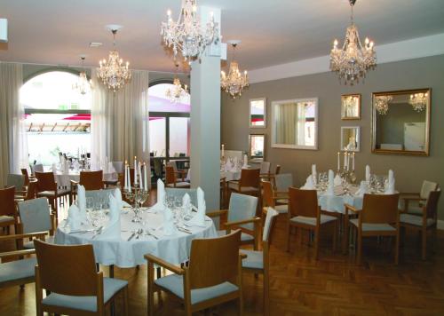 a dining room with white tables and chairs and chandeliers at Hotel am Molkenmarkt in Brandenburg an der Havel