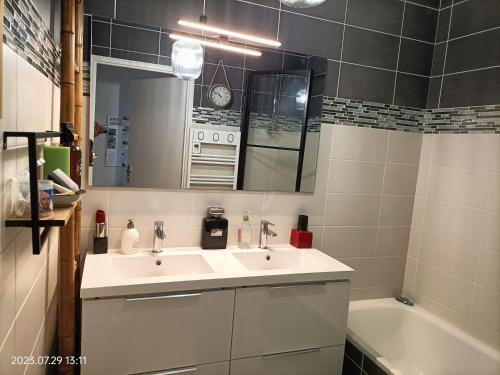 a bathroom with two sinks and a tub and a mirror at L'escale N°13 :Appartement standing dans résidence in Brest