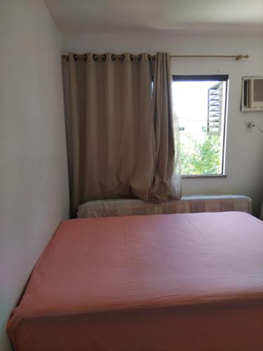 a bedroom with a large bed with a window at Apartamento em guarajuba 200m da praia in Camaçari