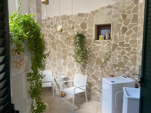 a bathroom with white chairs and a stone wall at Eterea Casa Vacanza in Brindisi