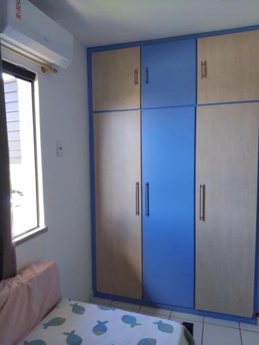 a room with blue cabinets and a bed and a window at Apartamento em guarajuba 200m da praia in Camaçari