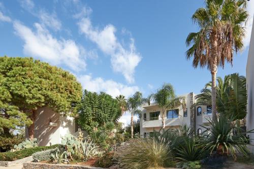 a house with palm trees and plants in front of it at Sentido Kyknos Beach Adults Only in Malia