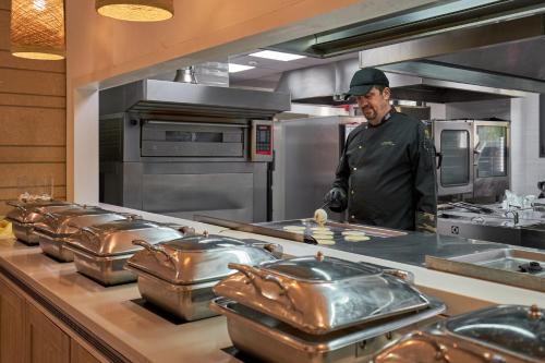 a chef standing in a kitchen with a bunch of pans at Sentido Kyknos Beach Adults Only in Malia