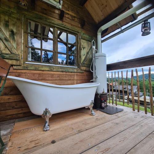 a white bath tub sitting on a wooden deck at Holzhütte allein am Waldrand in Saldenburg