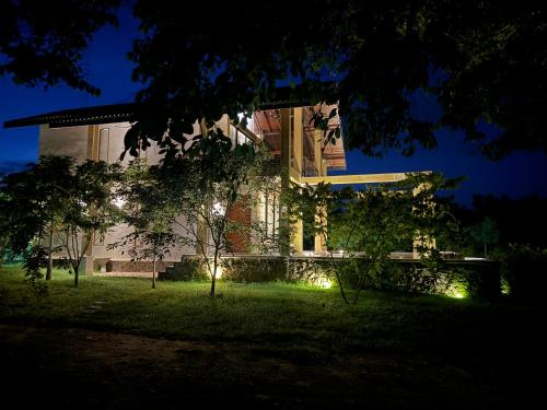 a building with lights in the yard at night at The Villa Lakeshore in Anuradhapura