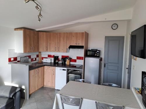 une cuisine avec des appareils électroménagers blancs et des armoires en bois dans l'établissement Gite 10 mn des plages, à Saint-Coulomb