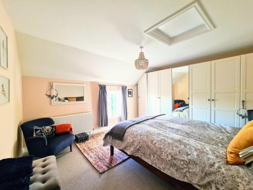 ein Schlafzimmer mit einem großen Bett und einem blauen Stuhl in der Unterkunft Brisley North Norfolk cosy cottage garden pub and walks in Beetley