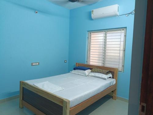 a bed in a blue room with a window at Mani Kasthuri Illam in Tiruvannāmalai