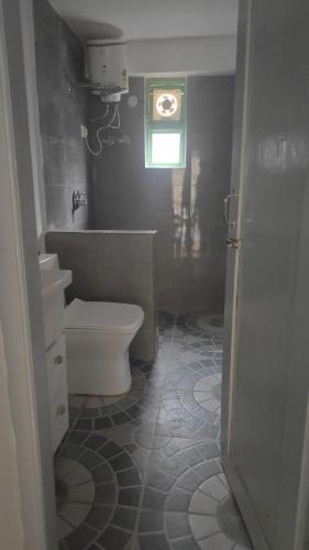 a bathroom with a toilet and a sink and a window at The Eleventh homestay in Kasol