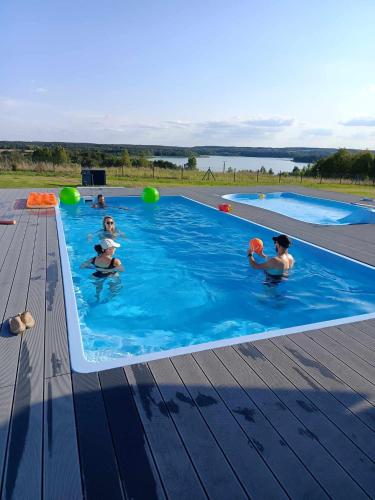 a group of people playing in a swimming pool at Domki Rekreacyjne "Błękitne Wzgórze" in Żałe