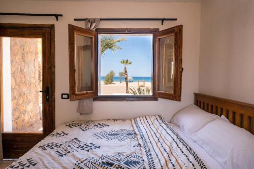 a bedroom with a bed and a window with a view of the beach at Sukoon Nuweibaa in Nuweiba