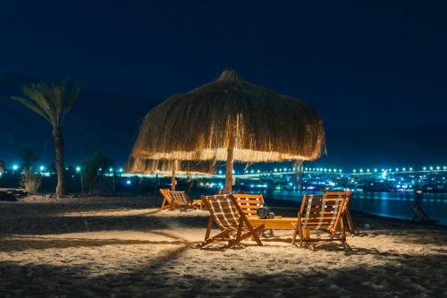 a group of chairs and an umbrella on the beach at night at Sukoon Nuweibaa in Nuweiba
