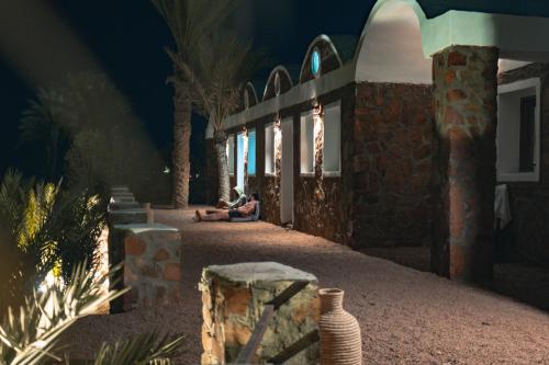 a woman sitting on the ground in front of a building at Sukoon Nuweibaa in Nuweiba