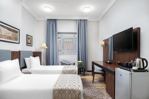 a hotel room with two beds and a desk at Elaf Bakkah Hotel in Makkah