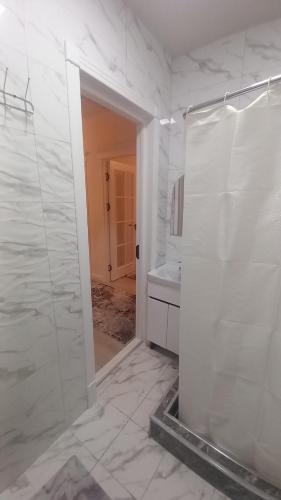 a white bathroom with a shower and a sink at Lux apartment in Ak-Tyube