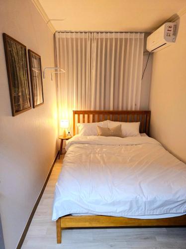 a bedroom with a white bed with a window at Busan Subway 6min #2 Rooms #2 Queen Beds #Hotel Bedding #OTT #Table#1st Floor in Busan