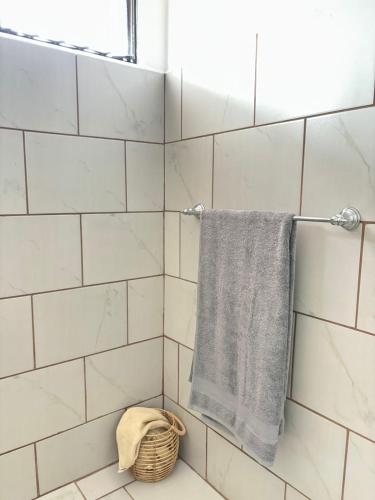 a white tiled shower with a towel and a basket at La Terraza Orgánica in Cartago