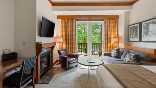 a living room with a couch and a fireplace at 1206 Lodge At Spruce Peak Ski In Ski In Ski Out King Studio By Stowe Mountain Rentals in Stowe