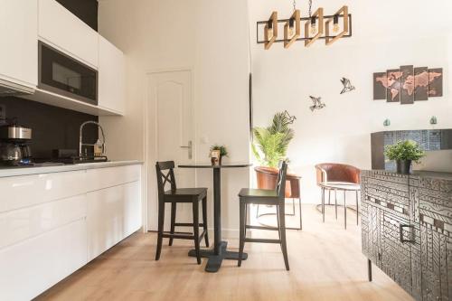 une cuisine avec des chaises, une table et un comptoir dans l'établissement L'Exotique - Hypercentre - Gare, à Angers