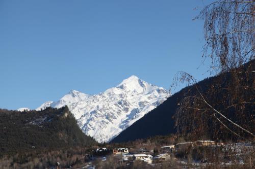 a snow covered mountain with a village in front of it at Guesthouse David Zhorzholiani in Mestia
