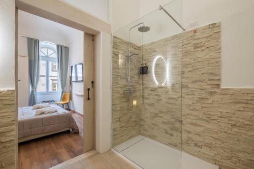 a bathroom with a walk in shower next to a bed at Via Roma 106 Apartment in Sassari