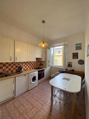 une cuisine avec une table et une table et une cuisine avec un évier dans l'établissement appartement Cyrnos 3Pc 73m2, à Ajaccio