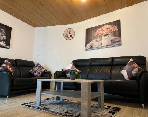 a living room with a black leather couch and a table at Via Roma 257 Apartament in Cochem