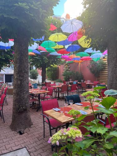 a patio with tables and chairs with umbrellas at Hôtel & Restaurant Le Patio VICHY in Vichy