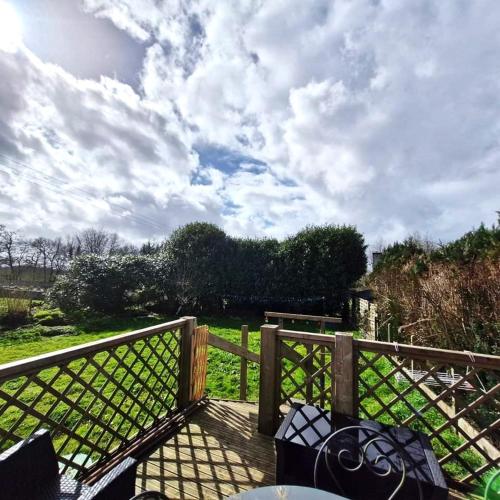 a deck with a fence and a view of a field at LE VERT NOMADE in Glomel