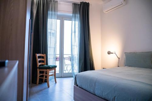 een slaapkamer met een bed, een stoel en een raam bij LemonHouse in Napels