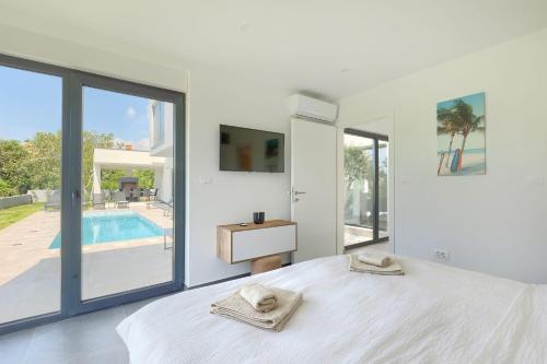 a bedroom with a white bed and a swimming pool at Villa Vivre in Ližnjan
