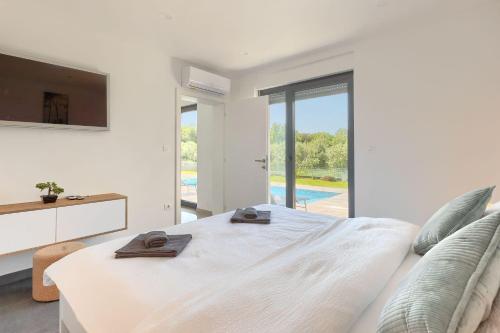 a white bedroom with a large bed and a tv at Villa Vivre in Ližnjan